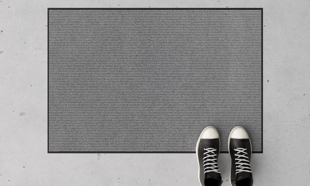 Blank gray door mat on the floor at home. Welcome mat with copy space for your text. Doormat mock up