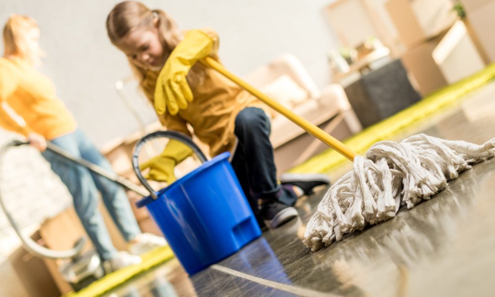 cute little girl with mop and bucket cleaning new apartment