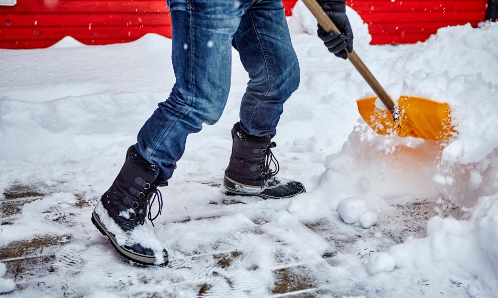 Man shovelling snow from pathway, low section